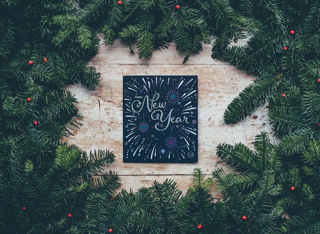 image of christmas greenery surrounding a sign saying 'happy new year'