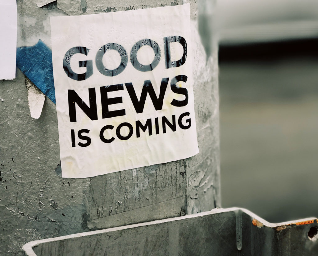 sign on a lamppost with the text 'good news is coming'