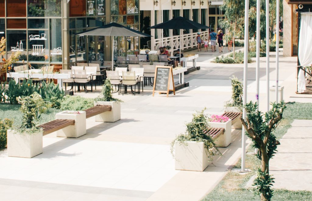 Image showing sunny, car-free area of cafe seating, trees, benches and green spaces